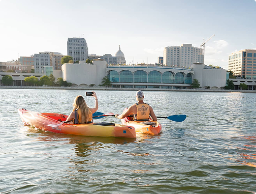people in kayaks on lake looking at monona terrace